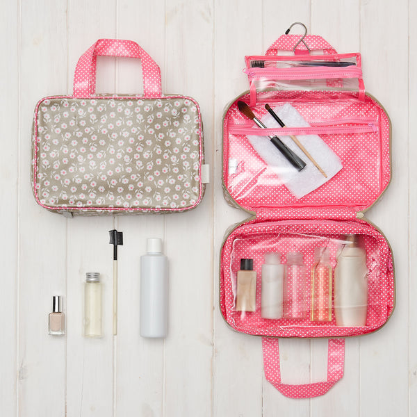 hanging toiletry bag in daisy sage with pink handles and transparent compartments